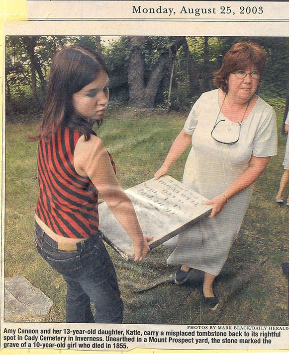 Amy Cannon and her 13-year-old daughter, Katie, carry a misplaced tombstone back to its rightful spot in Cady Cemetery in Inverness. Unearthed in a Mount Prospect yard, the stone marked the grave of a 10-yr-old girl who died in 1855.